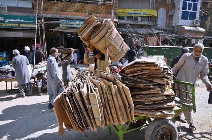 Labourers are busy loading cardboard onto the handcart at Raja Bazaar