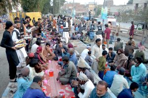 Volunteers distribute food items during Free Iftar at the roadside in Latifabad to deserving people, break their fast in the holy fasting month of Ramazan