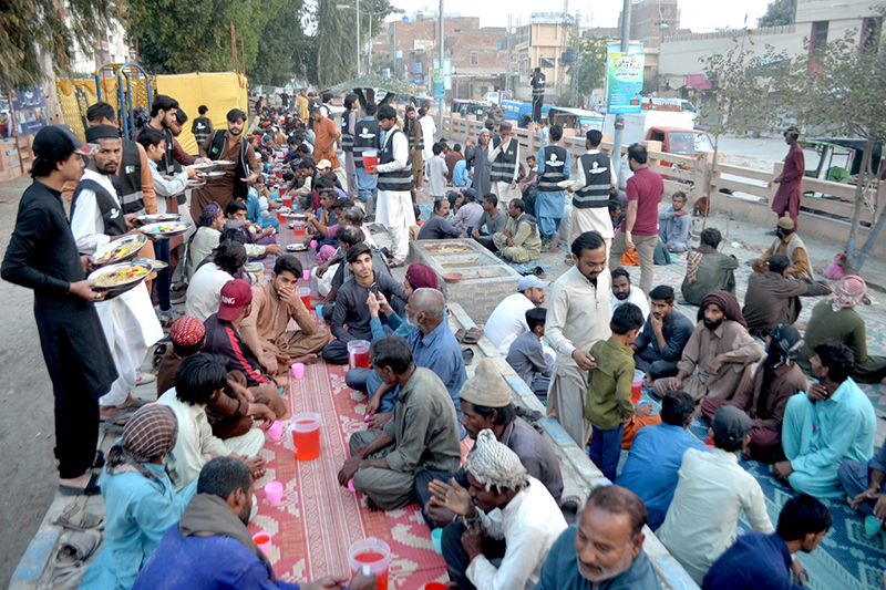 Volunteers distribute food items during Free Iftar at the roadside in Latifabad to deserving people, break their fast in the holy fasting month of Ramazan