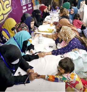 A girl being decorated her hand with Hinna (Mehndi) during the Eid Free Bazaar “Maa Hum Bhi Eid Manyen Gay” organized by JDC Welfare Foundation