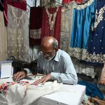 An elderly tailor stitching clothes at his shop ahead of the upcoming Eid-ul-Fitr