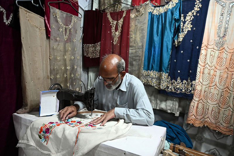 An elderly tailor stitching clothes at his shop ahead of the upcoming Eid-ul-Fitr