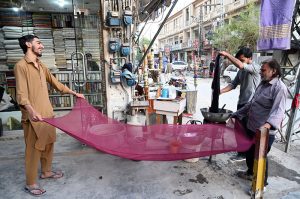 An elderly tailor stitching clothes at his shop ahead of the upcoming Eid-ul-Fitr