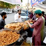 Customers purchase food items from a roadside stall to break their fast during Iftar in the holy month of Ramazan at G-9 market