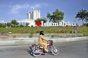 A motorcyclist crosses in front of the newly installed “I Love Islamabad” sculpture at the Convention Center, enhancing the beauty of the federal capital