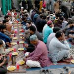 A large number of people break their fast during Free Iftar at the roadside in the city