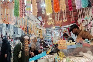 Women are busy selecting and purchasing artificial jewelry from stall at local market in connection with upcoming Eid ul Fitr.
