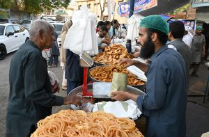 Customers purchase Samosa and Pakora from a roadside stall for Iftar to break their fast during the holy month of Ramazan at F-6 area in the Federal Capital.