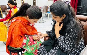 A female worker applies mehndi on a woman’s hand at a beauty salon in Resham Gali ahead of Eid-ul-Fitr