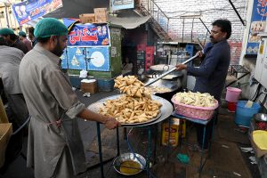 Customers purchase Samosa and Pakora from a roadside stall for Iftar to break their fast during the holy month of Ramazan at F-6 area in the Federal Capital.