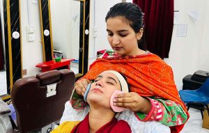 A female worker applies mehndi on a woman’s hand at a beauty salon in Resham Gali ahead of Eid-ul-Fitr