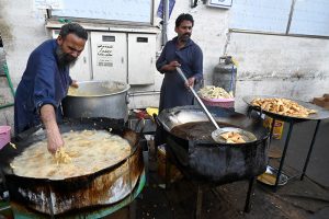 Customers purchase Samosa and Pakora from a roadside stall for Iftar to break their fast during the holy month of Ramazan at F-6 area in the Federal Capital.