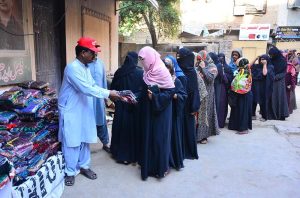 Volunteer distributes gifts to poor and deserving women ahead of the upcoming Eid al-Fitr at Edhi Foundation center.