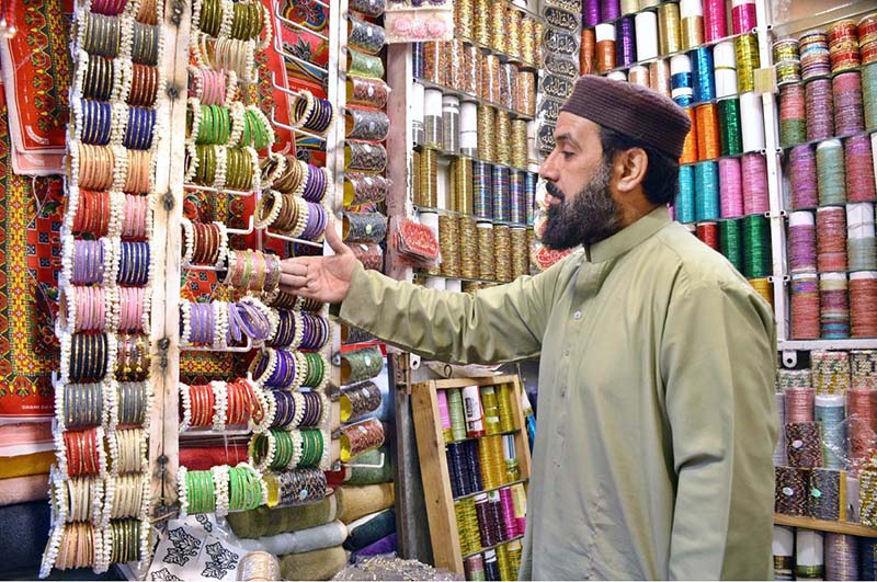 A shopkeeper displaying bangles in a local market to attract the customers in connection with upcoming Eidul Fitr