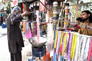 A worker dying clothes at his workplace for customers as people starts preparation for the upcoming Eidul Fitr celebrations at G-9 market in the Federal Capital