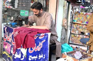 A worker dying clothes at his workplace for customers as people starts preparation for the upcoming Eidul Fitr celebrations at G-9 market in the Federal Capital