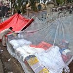 A vendor covers his roadside stall near the Girls College with a plastic sheet to protect it from the rain that the city is experiencing
