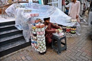A vendor covers his roadside stall near the Girls College with a plastic sheet to protect it from the rain that the city is experiencing
