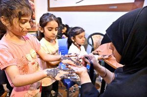 Young girls are decorating their hands with henna (Mehndi) in preparation for Eid-ul-Fitr at the Press Club