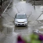 A view of a vehicle making its way through accumulated rainwater as showers hit the city