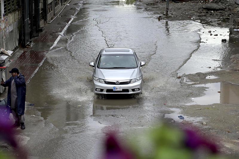 A view of a vehicle making its way through accumulated rainwater as showers hit the city