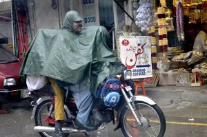 A motorcyclist on the way, under cover of a raincoat to protect from the rain, experienced the Twin Cities.