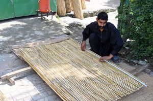 A worker prepares chick curtains at his workplace in the city