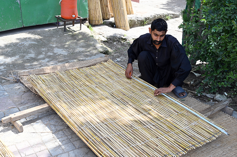 A worker prepares chick curtains at his workplace in the city