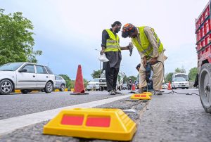 CDA workers install road studs along Islamabad Expressway near Faizabad Interchange to enhance night-time visibility and road safety.