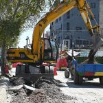 A worker operates heavy machinery to dig a trench for laying an underground water supply line in Khayaban-e-Sir Syed