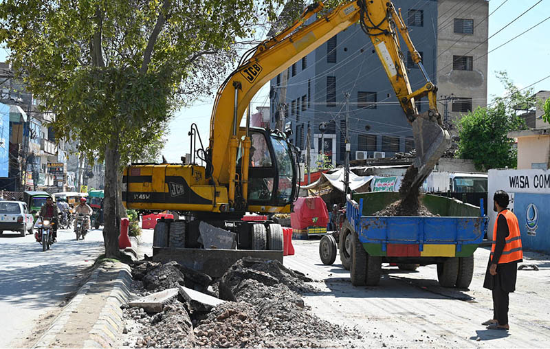 A worker operates heavy machinery to dig a trench for laying an underground water supply line in Khayaban-e-Sir Syed