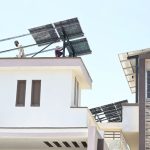 Technicians mount solar panels on a residential rooftop as urban families increasingly turn to renewable energy to hedge against skyrocketing electricity tariffs