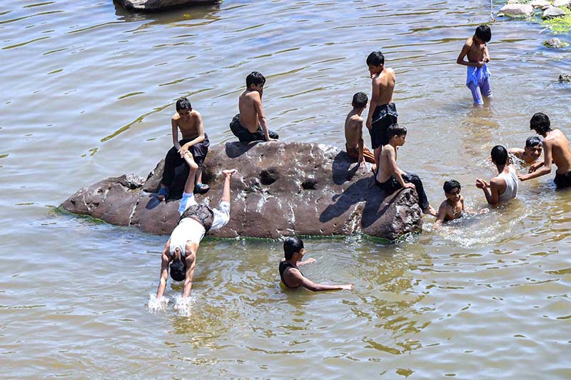 Youngsters are jumping and bathing in the Rawal Dam adjacent nallah as the mercury increases day by day in the Federal Capital