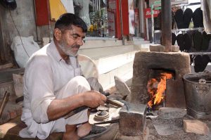 Blacksmith busy in making hand sickle at his workplace.