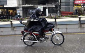 A motorcyclist on the way, under cover of a raincoat to protect from the rain, experienced the Twin Cities.