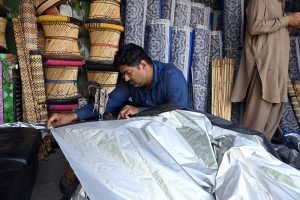 A worker prepares chick curtains at his workplace in the city