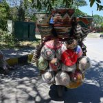 An elderly vendor displays household items on his bicycle while waiting for customers along a roadside near the I-8 area in the Federal Capital