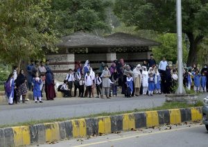 School students, accompanied by their teachers and parents, wait for public transport at the G-8 bus stop after school hours, heading back to their homes in the federal capital.