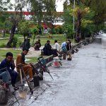 Daily-wage laborers wait for customers with their tools while sitting along the roadside near the G-8 area in the Federal Capital