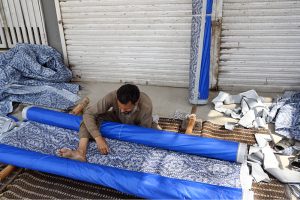 A worker prepares chick curtains at his workplace in the city