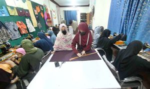 A tailoring instructor guides a trainee during a garment stitching class at Fixit Skill Centre. 