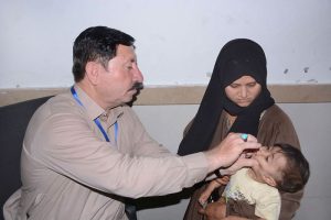 A health worker administers polio vaccine to a baby as the mother holds the child during a campaign in the city.