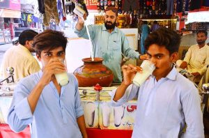 People gather around a roadside vendor to drink traditional summer drink lassi for relief from the hot weather in the city.
