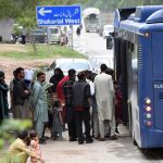 A large number of people stand in a queue to board an electric bus after the government announced free public transport amid rising petrol prices in the country