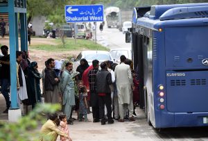 A large number of people stand in a queue to board an electric bus after the government announced free public transport amid rising petrol prices in the country
