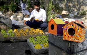 An artisan paints ladybird-themed garden décor at a roadside his setup in Chak Shahzad area in Federal Capital.