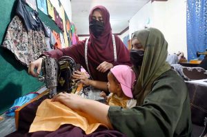 A tailoring instructor guides a trainee during a garment stitching class at Fixit Skill Centre. 