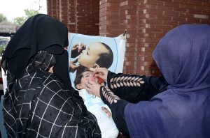 A health worker administers polio vaccine to a baby as the mother holds the child during a campaign in the city.