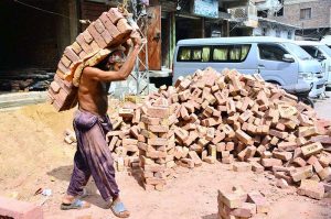A labourer is shifting bricks during construction work of a house