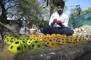 An artisan paints ladybird-themed garden décor at a roadside his setup in Chak Shahzad area in Federal Capital.